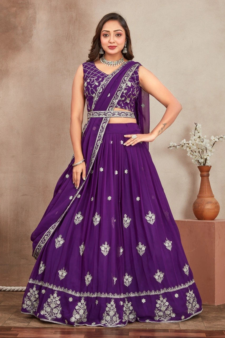 Woman wearing a purple embroidered saree with a matching blouse against a neutral background